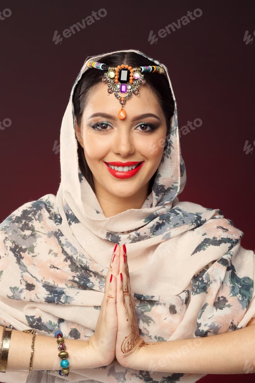 Preview: Woman in traditional dress greets with hands together while wearing jewelry