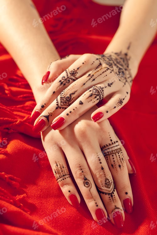 Preview: Hands with henna designs resting on a red fabric background during a vibrant celebration