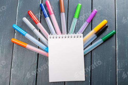 Preview: Markers and notebook are arranged on a wooden table in a creative setup for drawing
