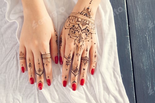 Preview: Hands with henna design and red nails resting on a white cloth background