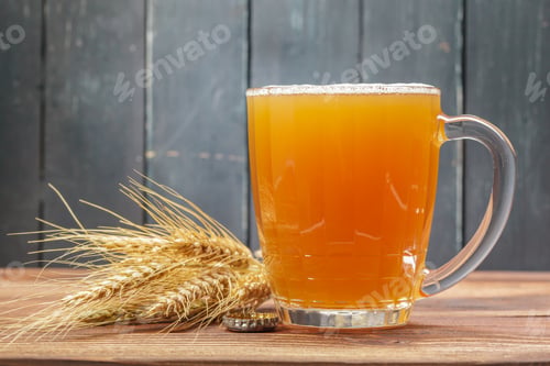 Preview: Craft beer in a clear mug next to wheat on a wooden table