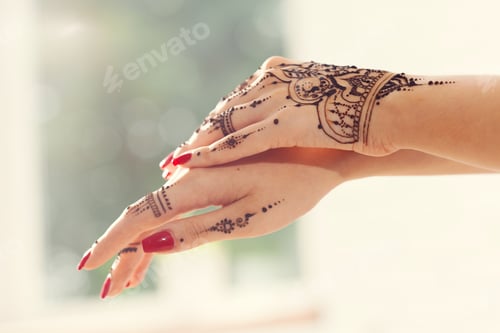 Preview: Intricate henna design on hands with bright nail polish during a cultural celebration