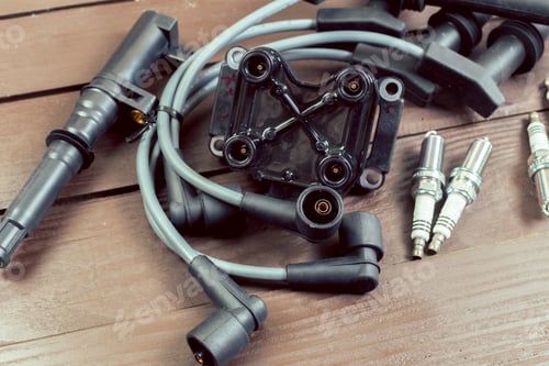 Preview: Car engine parts and wires are displayed on a wooden table in a workshop