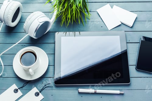 Preview: Working at a table with a tablet, coffee, headphones, and a plant in the morning