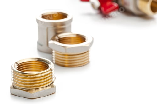 Preview: Different sizes of brass plumbing fittings arranged on a white surface in a workshop