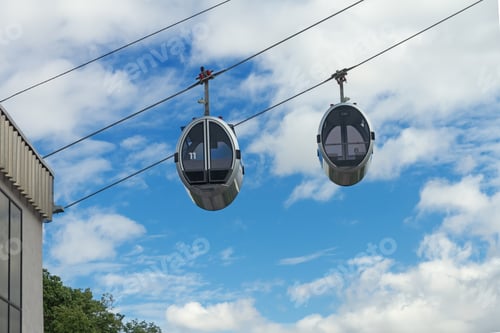 Preview: Modern cable car cabins moving against blue sky