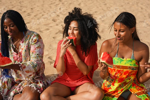 Preview: Happy young multiracial women having fun eating watermelon on the beach
