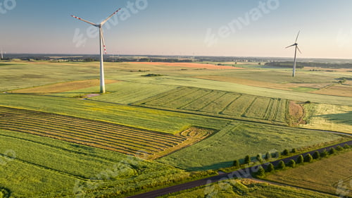Preview: Wind turbines on green field in spring at sunrise