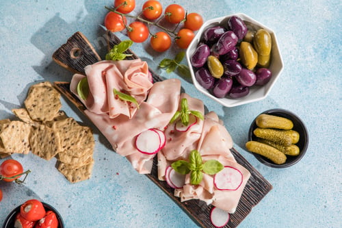 Preview: Slices Of Traditional Italian antipasti mortadella Bolognese on a wooden cutting board.