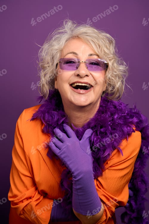 Preview: Senior woman laughing wearing purple boa and sunglasses