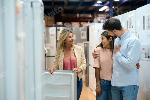 Preview: Saleswoman assisting couple choosing new refrigerator at appliance store