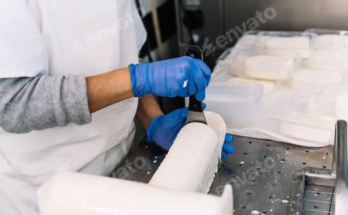 Preview: Worker hands cutting fresh cheese block in dairy factory