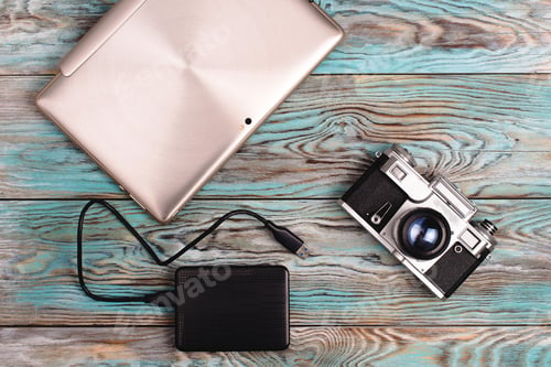 Preview: The tablet and camera lying on wooden blue background