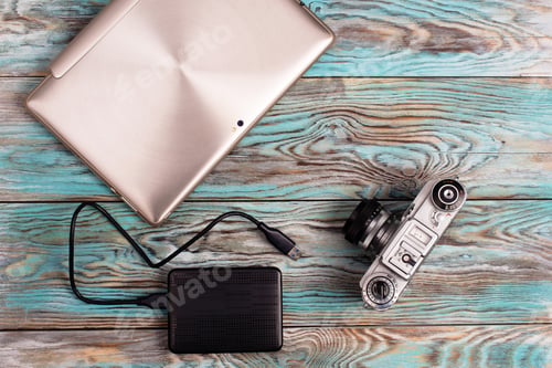 Preview: The tablet and camera lying on wooden blue background