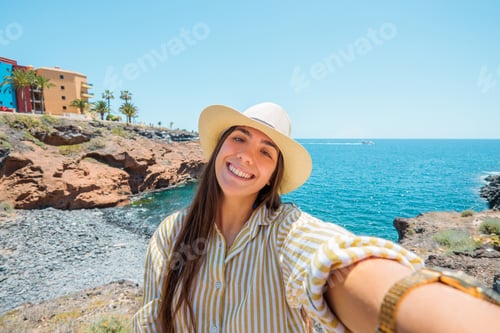 Preview: Woman smiling taking a selfie on coastal cliffs during summer vacation