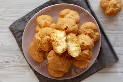 Preview: Homemade Mini Cream Puffs with Whipped Cream Filling on a Plate, top view.