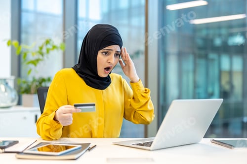 Preview: Deceived upset woman in hijab sitting inside office with laptop. Office worker received electronic a