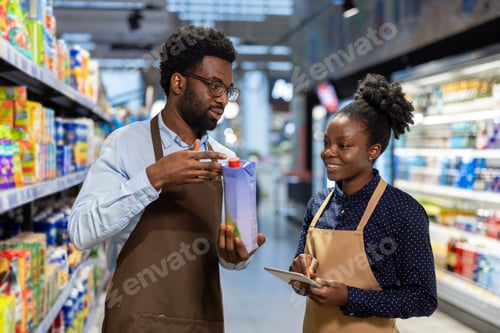 Preview: Supermarket workers checking product inventory with tablet