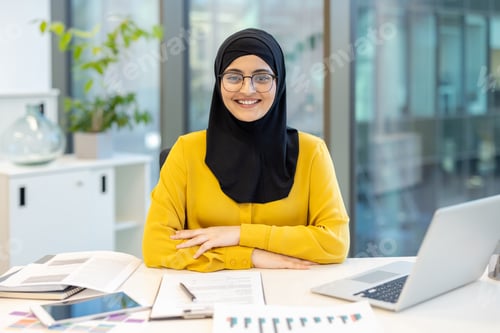 Preview: Muslim businesswoman smiling at desk in modern office