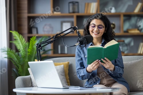 Preview: A smiling woman records a podcast while reading a book in a comfortable studio setting.