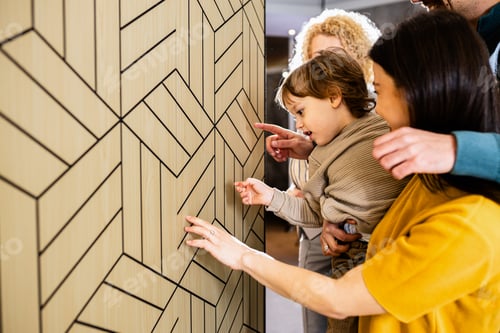 Preview: Saleswoman showing a young couple with a child the panels for decorating the interior of the home.