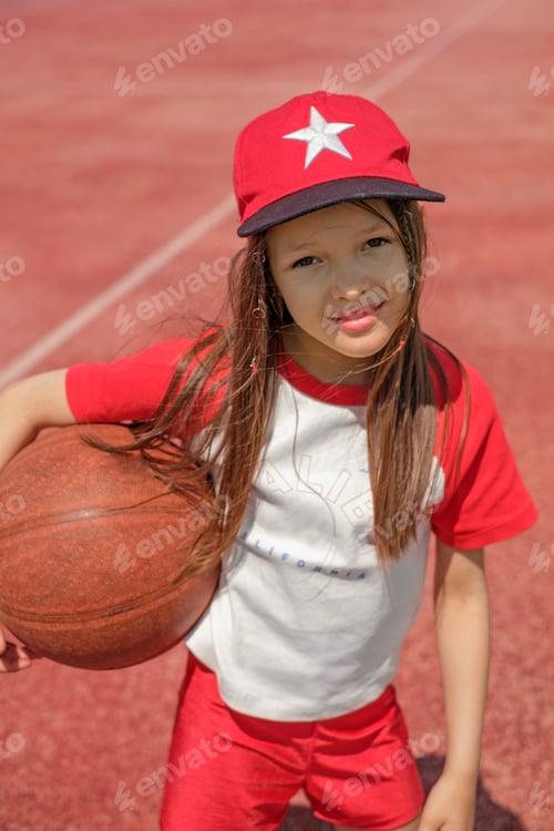 Preview: Portrait of a beautiful girl in a red sports cap with a basketball in her hand