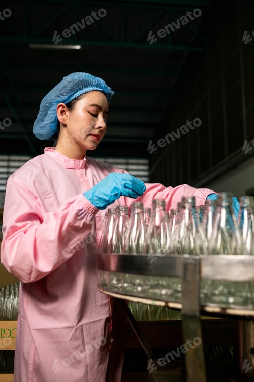 Preview: Worker inspecting empty glass bottles before filling process