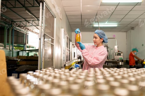 Preview: Female worker inspecting bottled beverage on production line