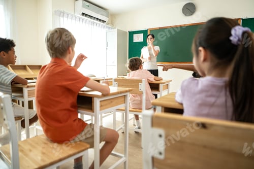 Preview: Schoolgirl presenting in front of class with teacher observing