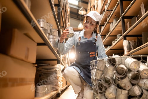 Preview: Small business worker carefully inspecting products in a warehouse