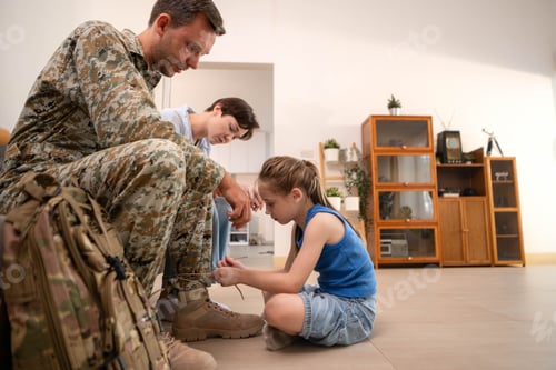 Preview: Daughter tying her soldier father's boots, capturing a tender moment of love