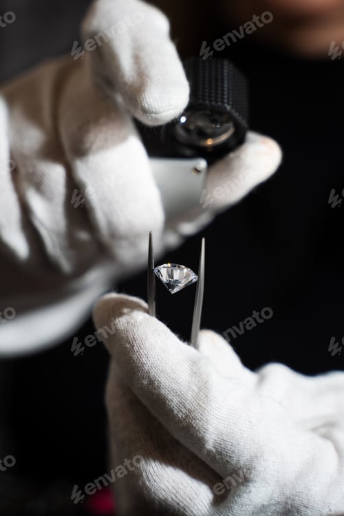 Preview: Close up of diamond examination with tweezers and loupe for quality assessment.