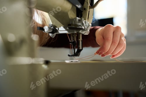 Preview: Artisan carefully threading an industrial sewing machine in a workshop setting.