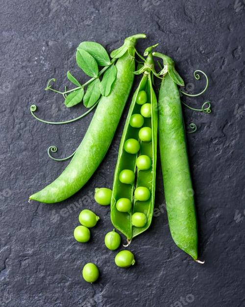 Preview: Green peas scattered on black surface with pods