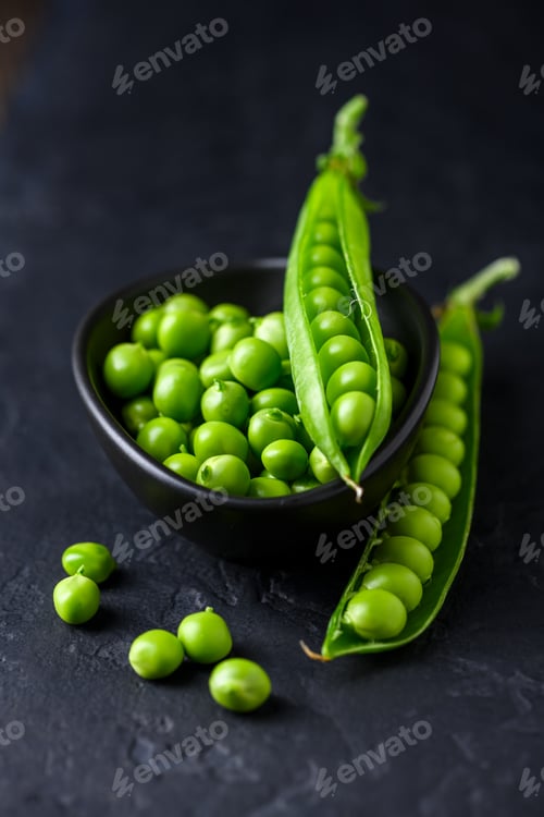 Preview: Fresh green peas in a black ceramic bowl with open pods