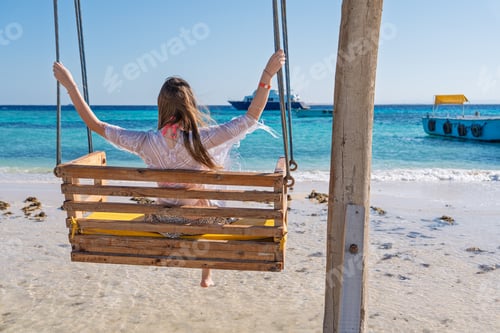 Preview: Woman relaxing on a swing at a tropical beach during a peaceful summer vacation in Sharm El She