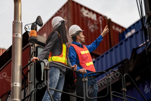 Preview: Two logistics workers man and woman discuss operations at a busy shipping container yard. successful