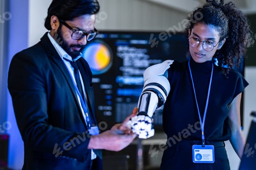 Preview: South Asian male IT analyst and Black female engineer with a robotic prosthetic arm collaborate in a