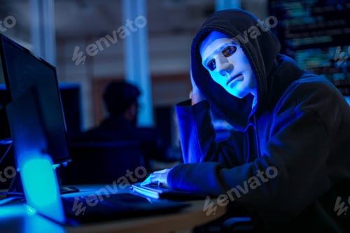Preview: Profile of a mysterious anonymous hacker in a black hoodie and white mask infiltrating a corporate n