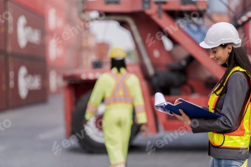 Preview: Team logistics workers in high visibility safety gear and hard hats discuss operations at a busy shi