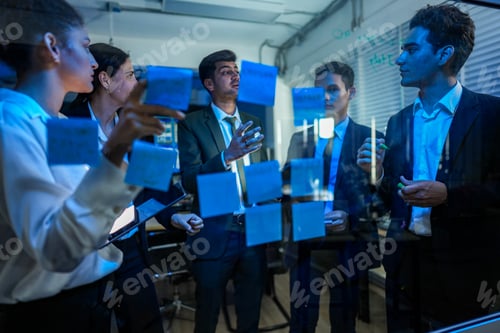 Preview: Collaborative business team placing sticky notes on a glass wall to map out project strategy in a mo