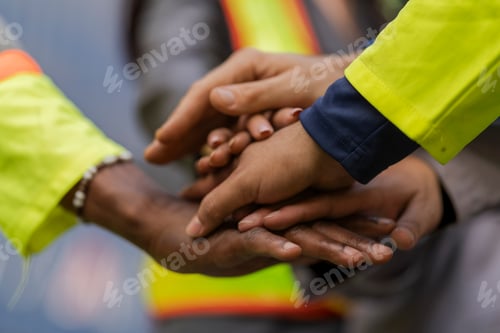 Preview: Team logistics workers in high visibility safety gear and hard hats discuss operations at a busy shi