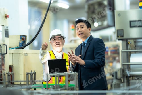 Preview: A confident factory manager in a professional business suit standing with arms crossed, overseeing i