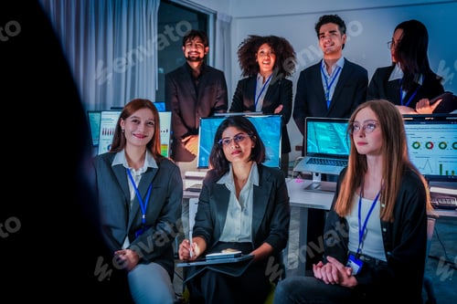 Preview: Group of attentive corporate professionals attending a nighttime training session. Diverse male and