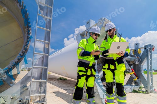 Preview: Two engineers in safety gear inspecting a wind turbine blade section on a construction site. They ex