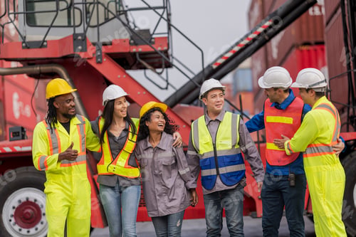 Preview: Team logistics workers in high visibility safety gear and hard hats discuss operations at a busy shi