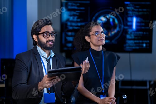 Preview: South Asian male security analyst and Black female tech engineer with a robotic prosthetic arm revie
