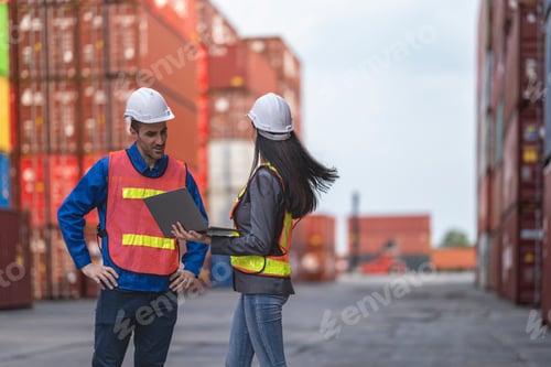 Preview: Two logistics workers man and woman discuss operations at a busy shipping container yard.