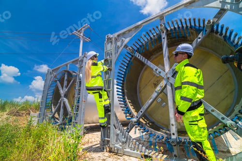 Preview: Two engineers in safety gear inspecting a wind turbine blade section on a construction site. They ex