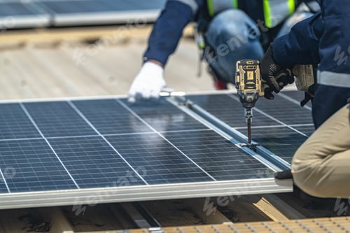 Preview: Detailed view of an installer's hands in protective gloves tightening bolts on a solar panel frame u